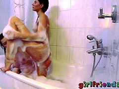 Kira Zen fingers her friend's shaved pussy in the bath with her big tits out